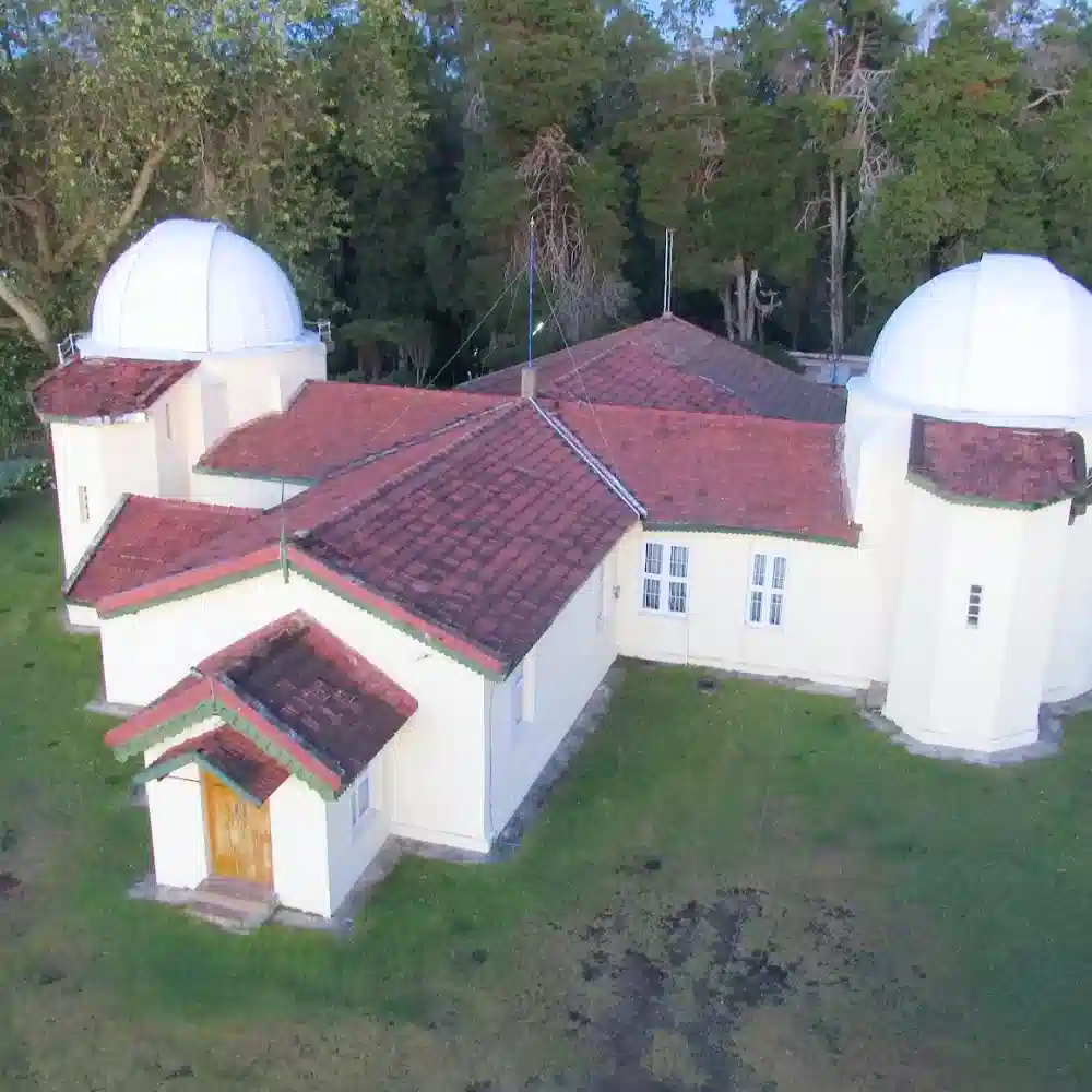 High angle view of the historic Kodaikanal Solar Observatory building with its white domes and red tiled roof tops.