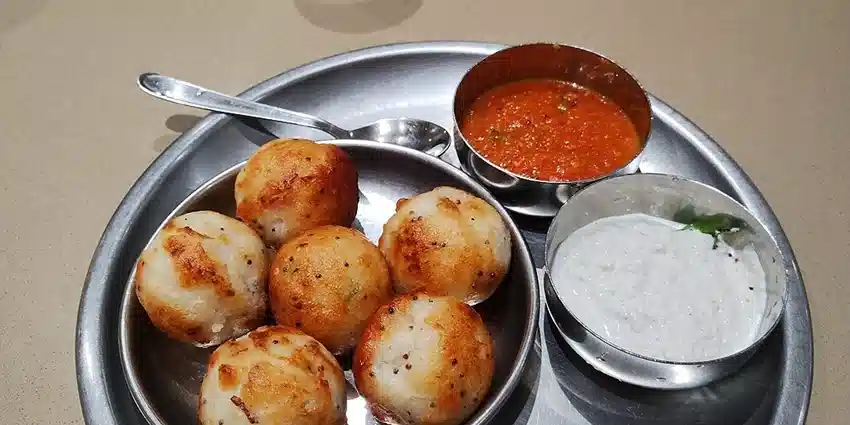 Delicious plate of Kuzhi Paniyaram served with spicy red tomato chutney and white coconut chutney in Kodaikanal hills.